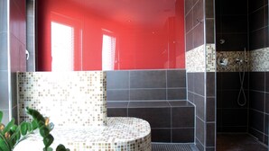 A modern bathroom with a red wall, a tiled bench, and a shower area. - Dormero Hotel Frankfurt Messe (Frankfurt)