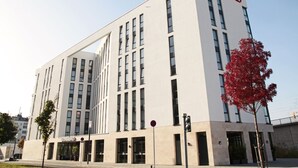 A modern Doriterno hotel with a flat facade, large windows, and a prominent red sign. - Dormero Hotel Frankfurt Messe (Frankfurt)