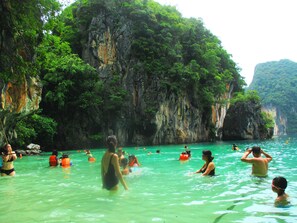 A group of people swimming in a natural water body surrounded by cliffs. - Happiness Resort (Krabi)