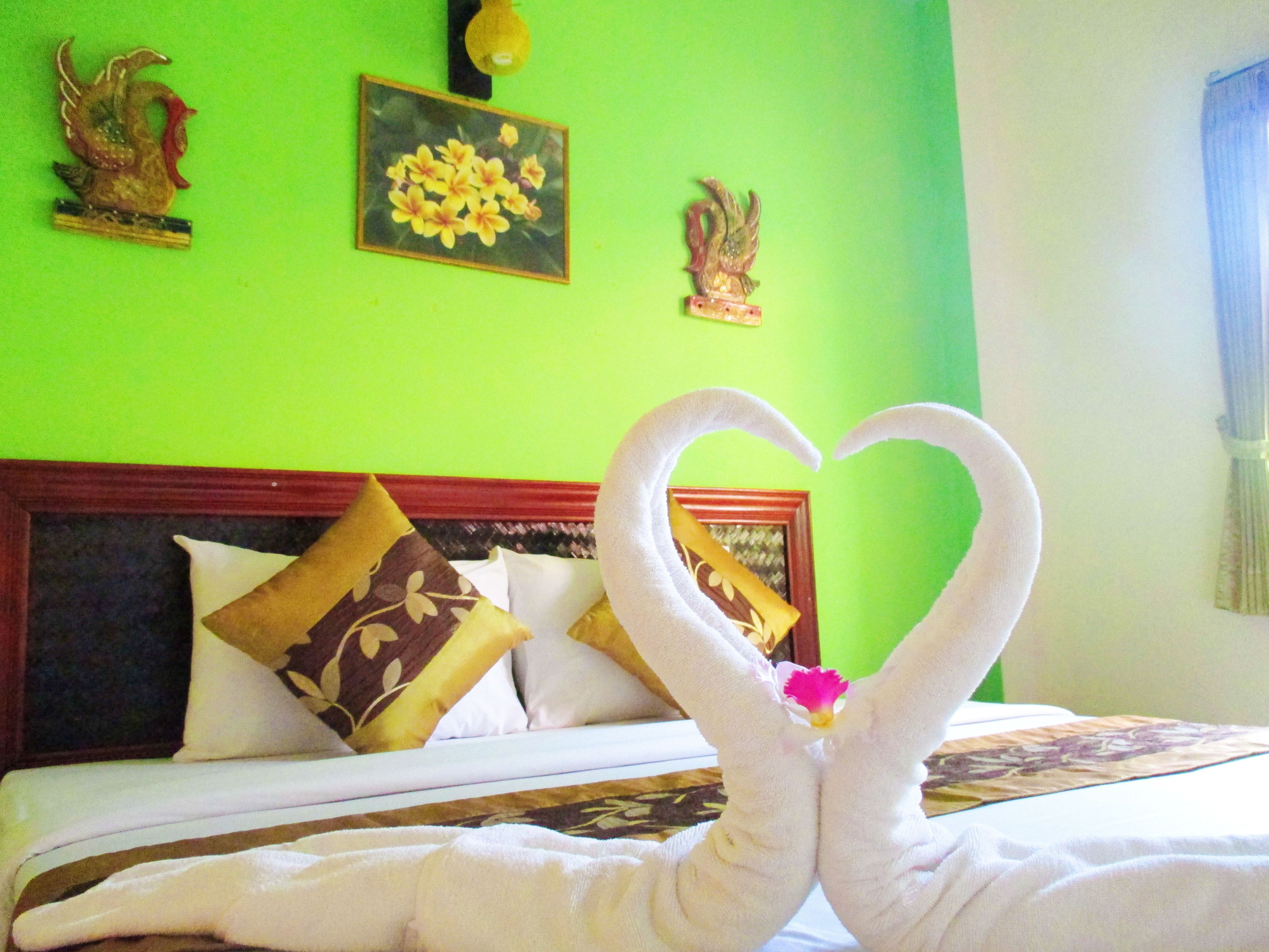 A hotel room with a bed, pillows, and a green wall.