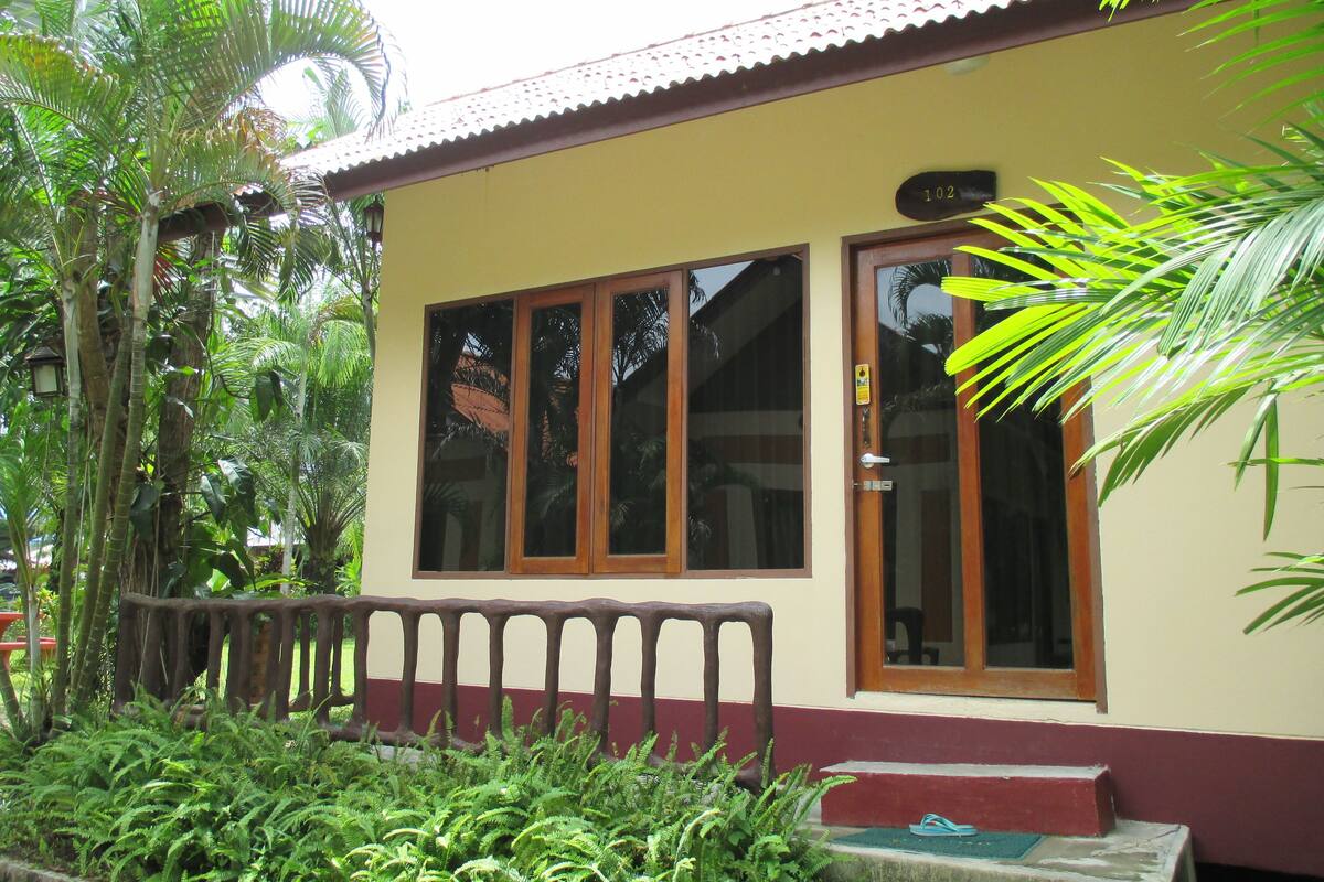 A building with large windows, a red and beige facade, and a wooden bench in front.