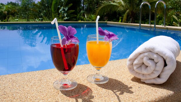 Two drinks with straws and a rolled towel by a poolside. - Happiness Resort (Krabi)