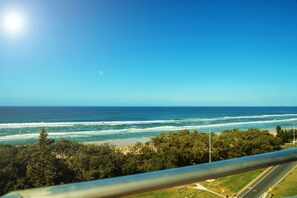 A coastal view with a road, beach, and forested area. - Equinox Resort (Surfers Paradise)