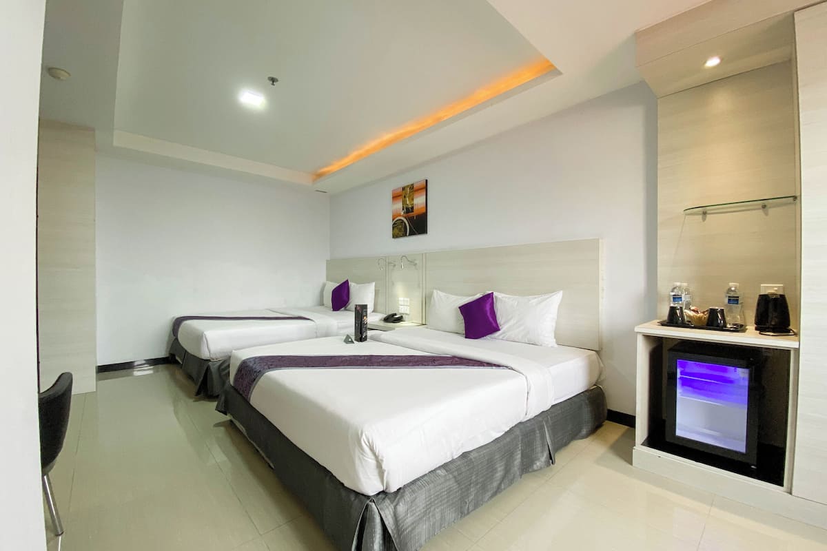 Habitación de hotel con dos camas, un escritorio, una silla y un minibar.