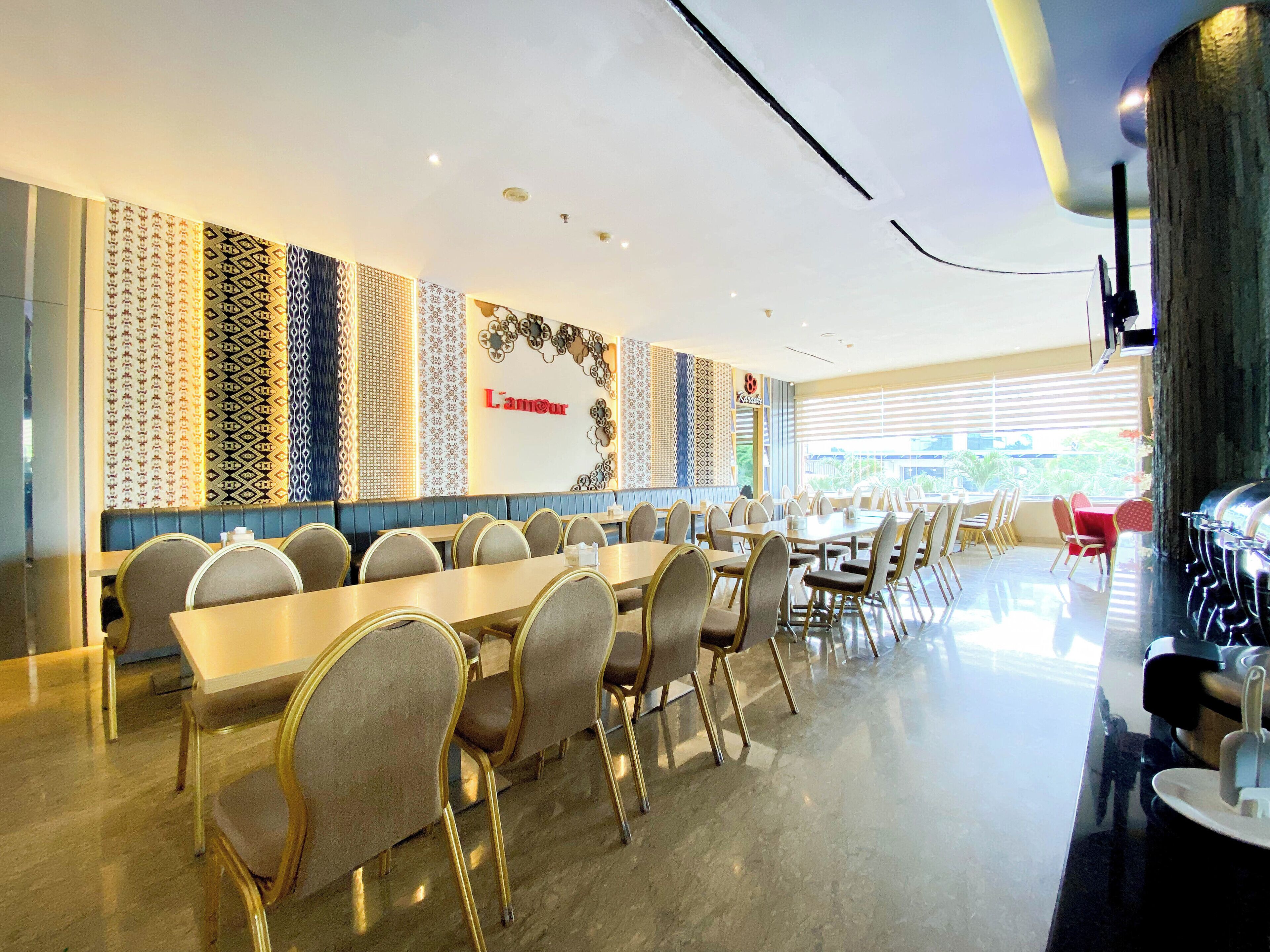 A spacious dining area with long tables and chairs, a decorative wall with patterns, and a sign that reads "L'Amour".
