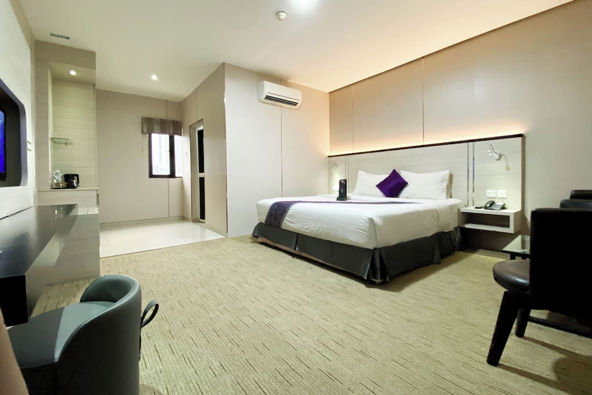 Una habitación de hotel moderna con una cama grande, un escritorio, una silla y un televisor.