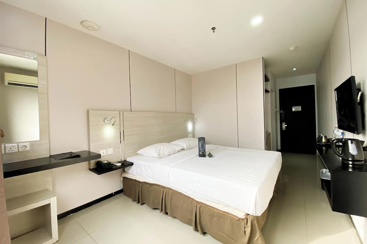 Una habitación de hotel moderna con una cama grande, una mesita de noche, un escritorio y un televisor de pantalla plana.