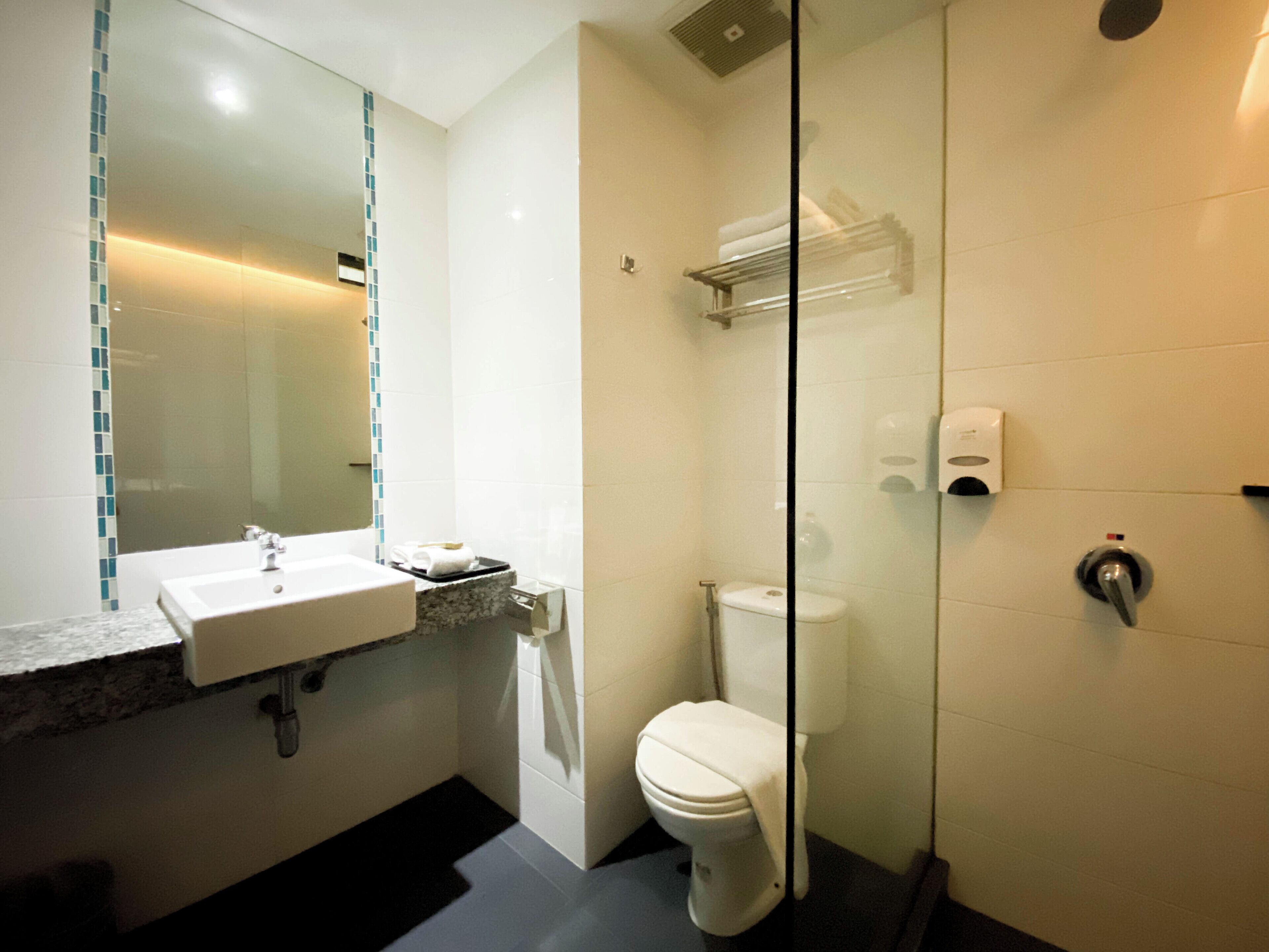 A modern bathroom with a glass shower enclosure, a white toilet, and a sink with a marble countertop.