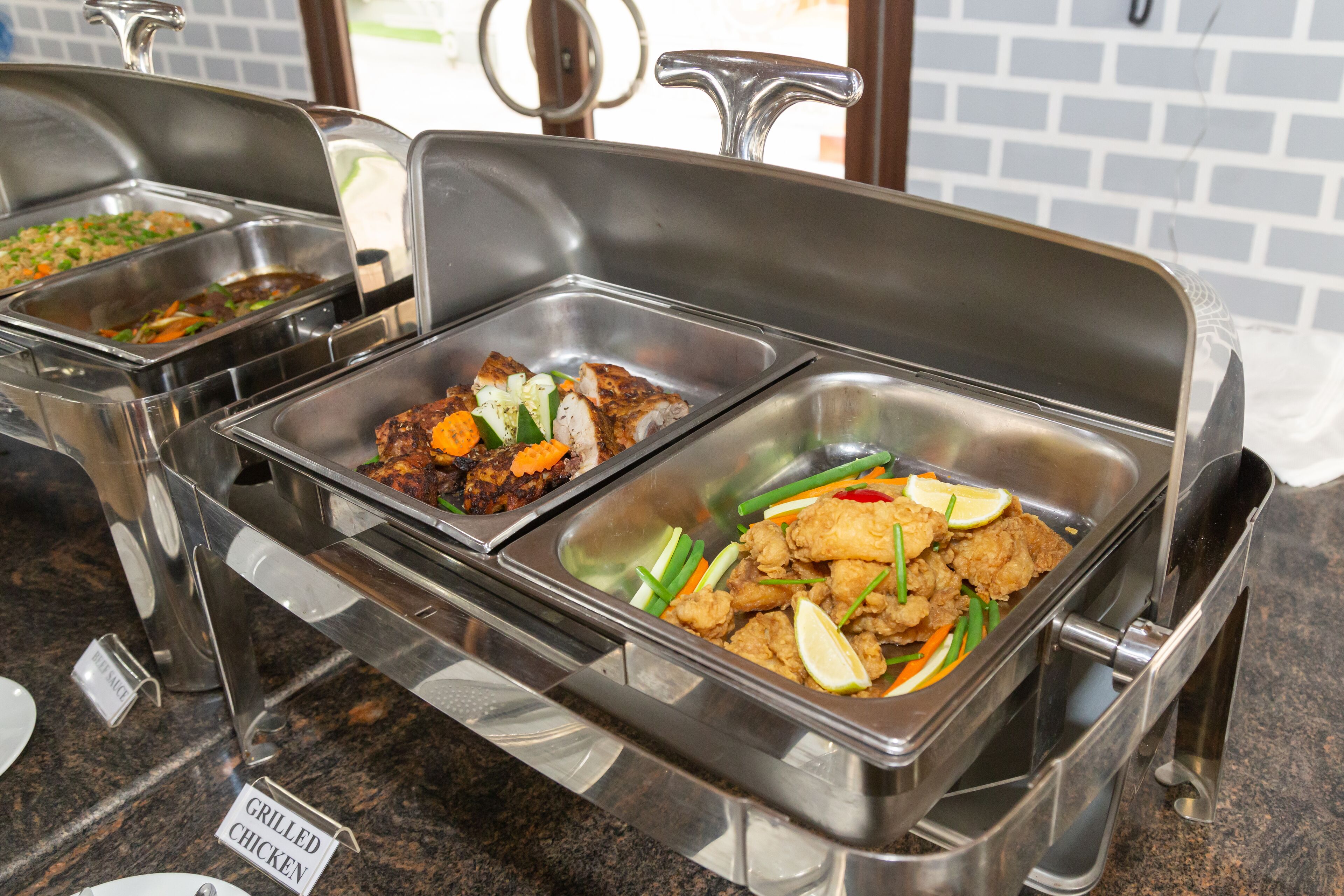 A buffet with labeled dishes including grilled chicken, vegetables, and other items.