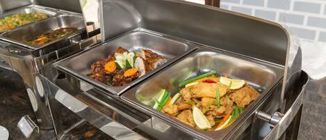 A buffet with labeled dishes including grilled chicken, vegetables, and other items.