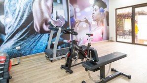 A gym with exercise equipment, a large wall mural, and a bench. - Sunlodge Hotel (Accra)
