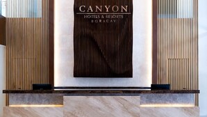 Un comptoir d’accueil avec une enseigne indiquant : « CANYON HOTELS & RESORTS BORACAY ».