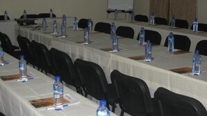 A conference room with long tables, black chairs, and water bottles on each table. - Rayporsh Hotel (Accra)