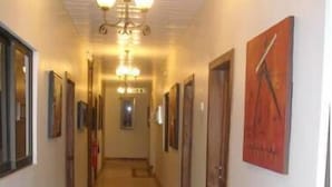 A hallway with a tiled floor, a chandelier, and framed artwork on the walls. - Rayporsh Hotel (Accra)