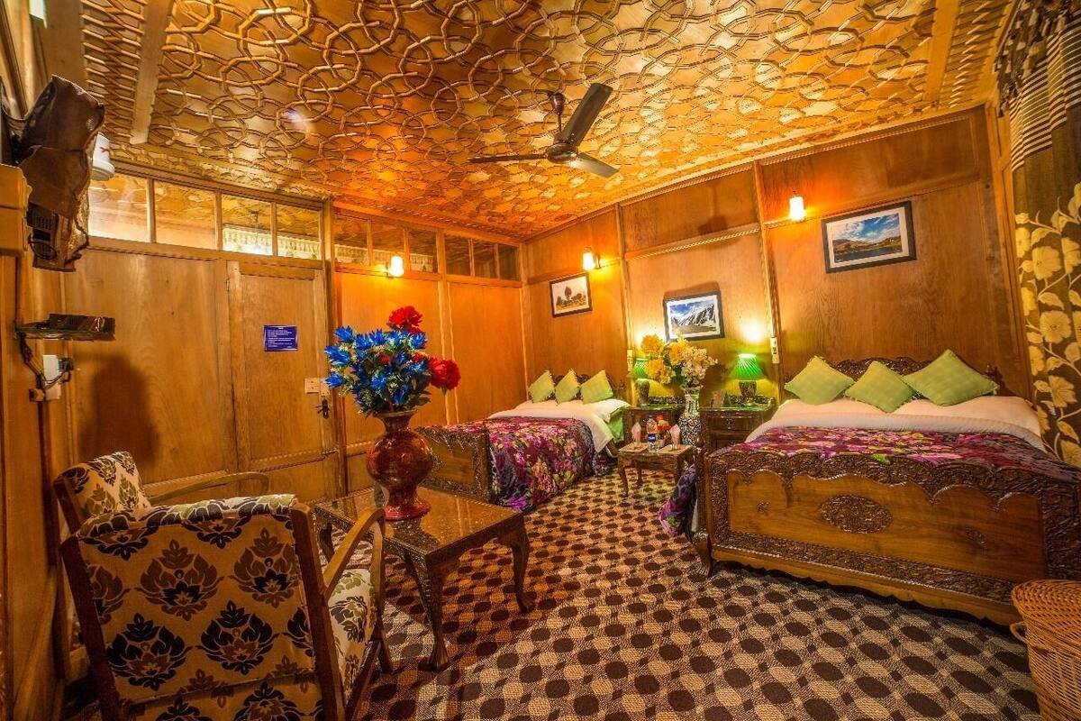 A room with two beds, a wooden ceiling, and a checkered floor.