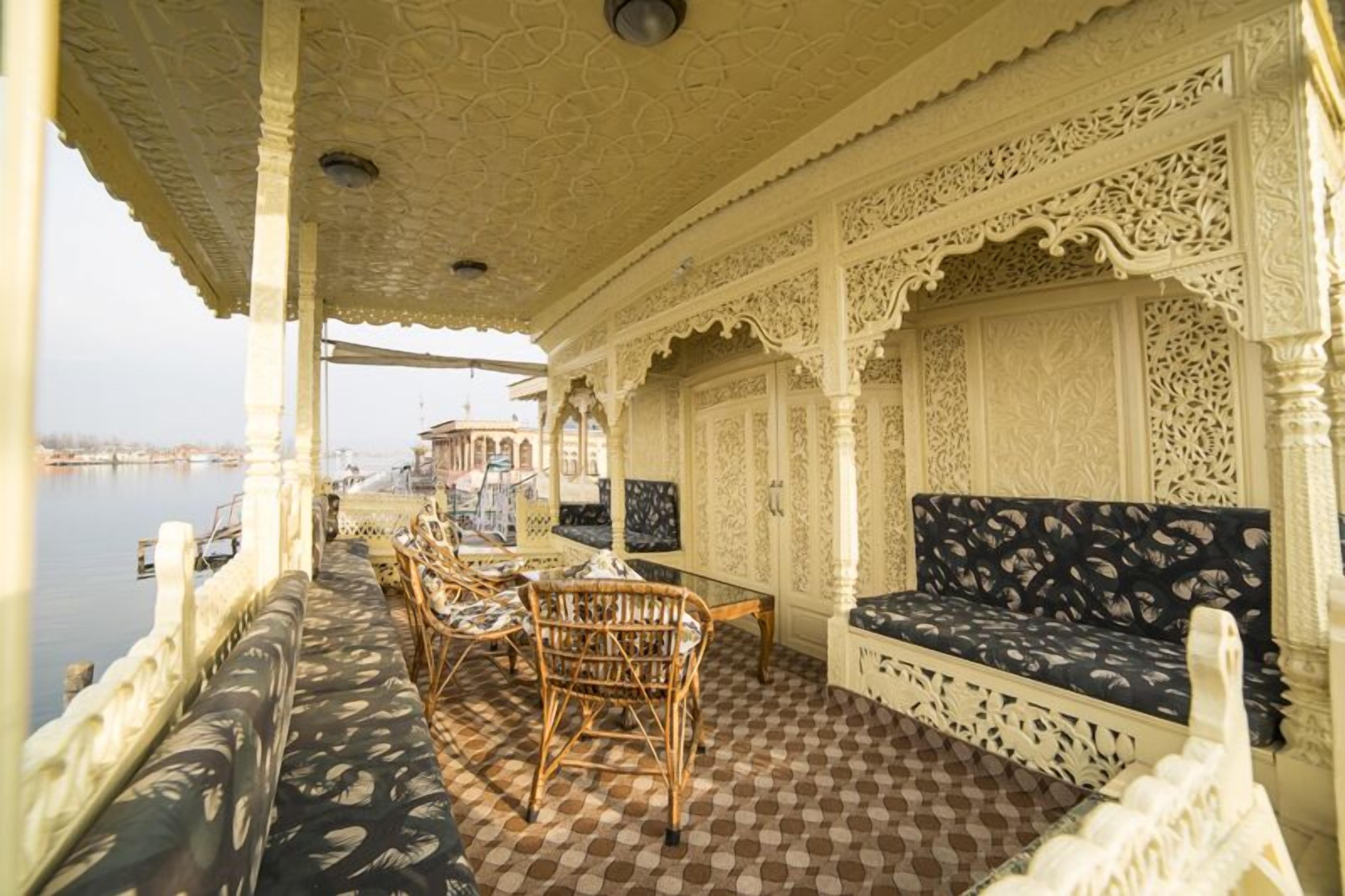Un espacio interior decorado con elegantes asientos, suelo con diseños, columnas blancas y elaborados motivos en las paredes.