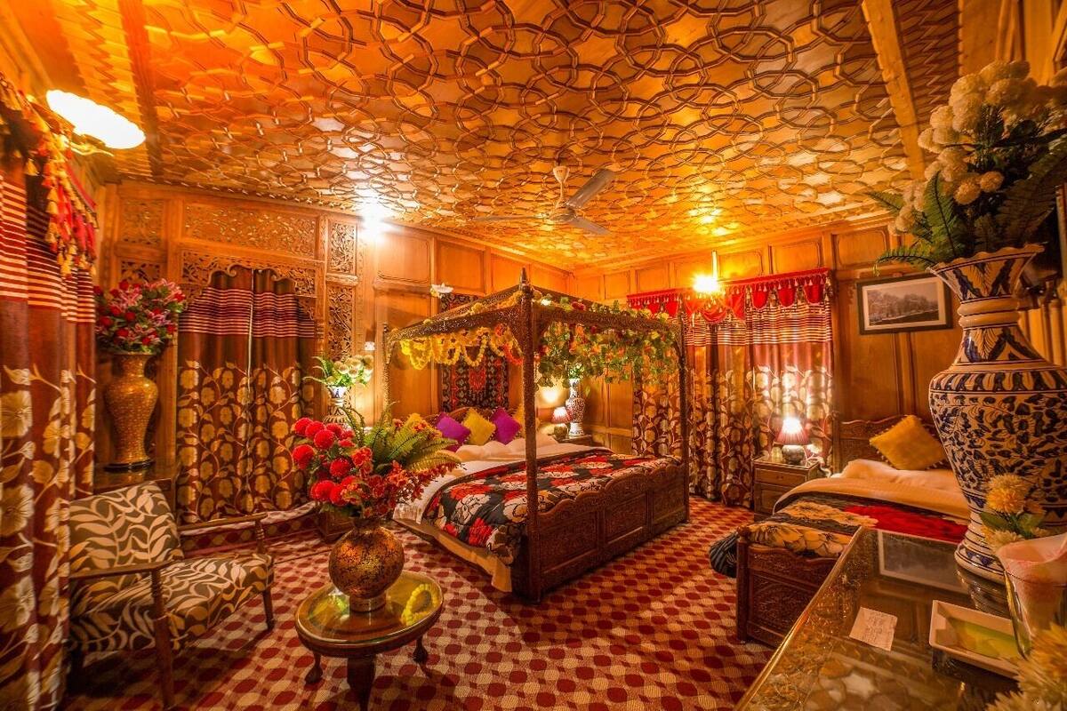 A traditional room with a four-poster bed, ornate ceiling, and floral decorations.