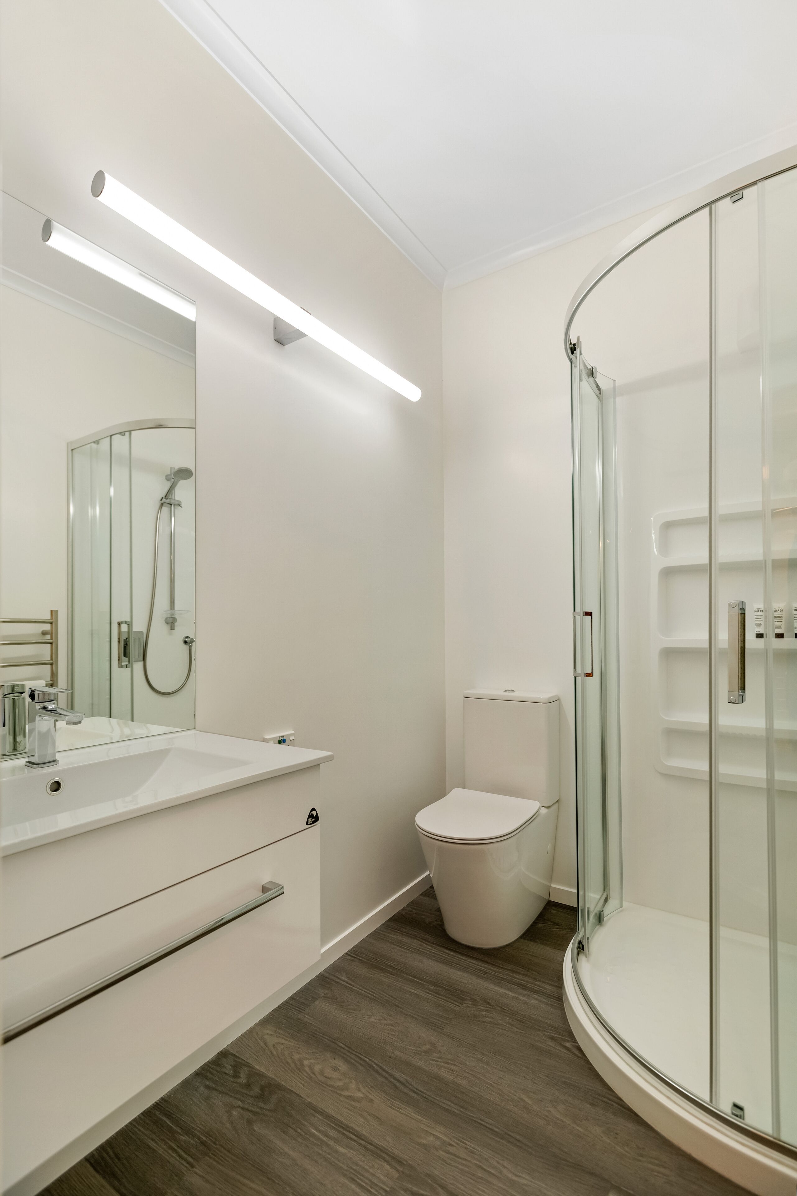 A modern bathroom with a glass-enclosed shower, a white sink, and a toilet.