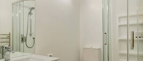 A modern bathroom with a glass-enclosed shower, a white sink, and a toilet.