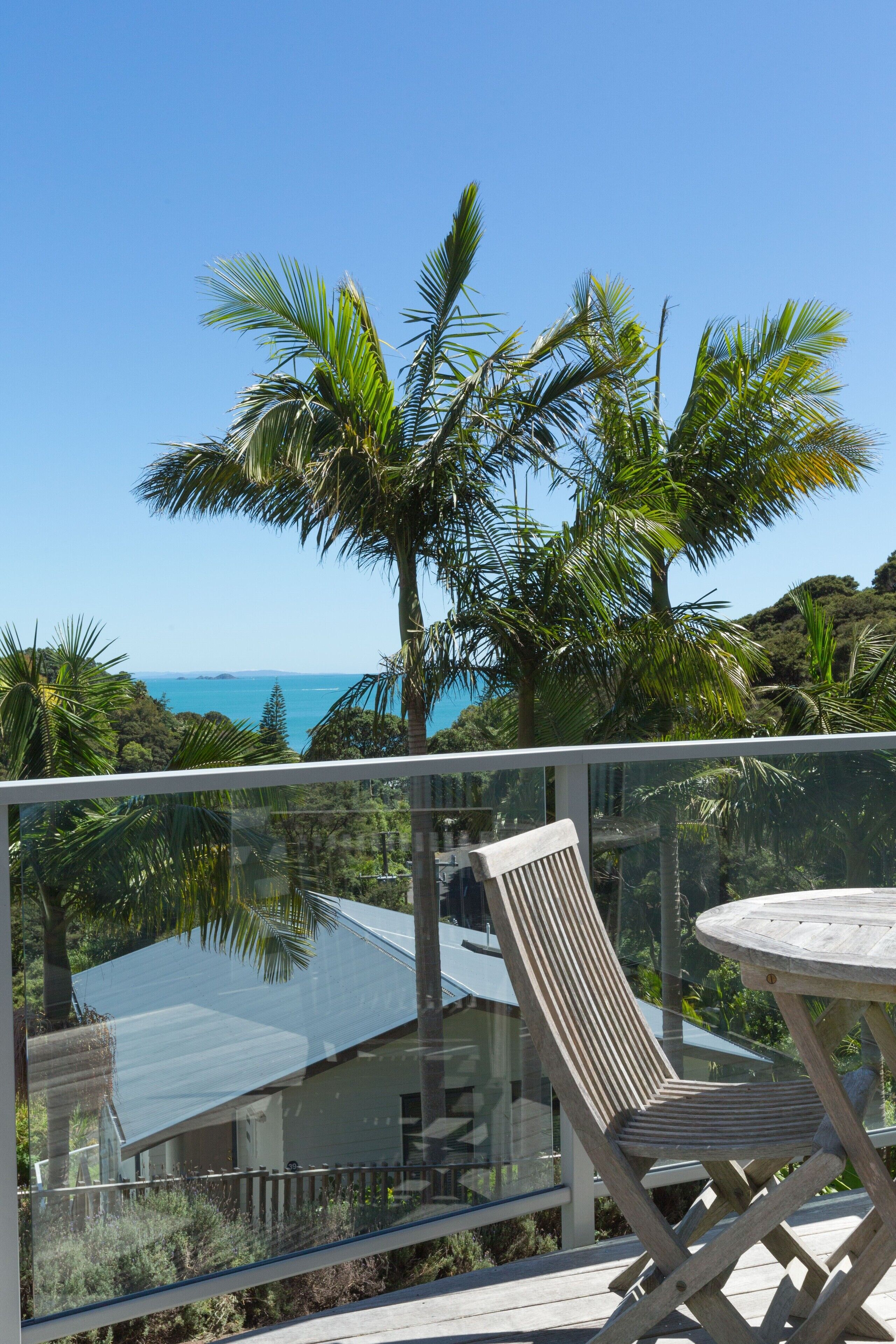 A balcony with a glass railing, a wooden chair, and a table.
