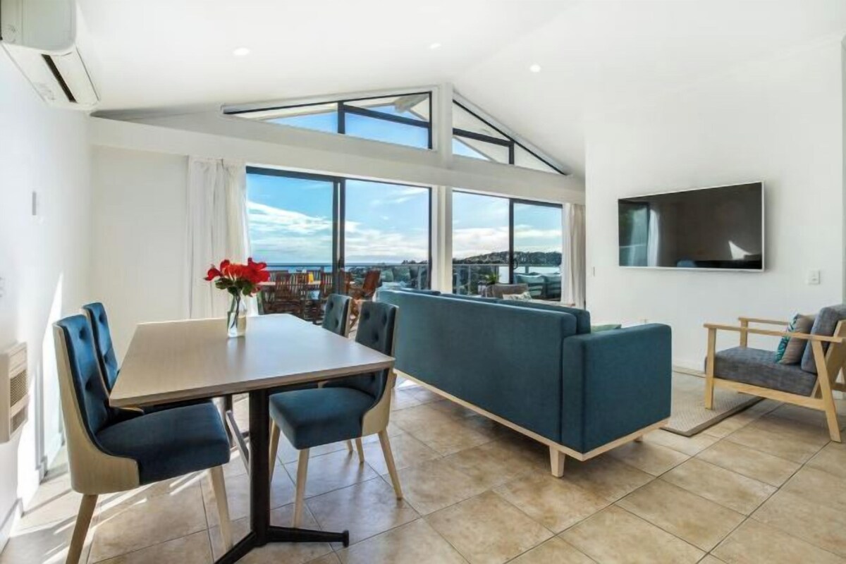 A modern interior with a dining area, seating, and a TV mounted on the wall.