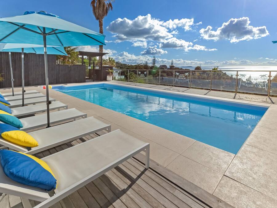Una piscina al aire libre, sombrillas, sillones reclinables de piscina
