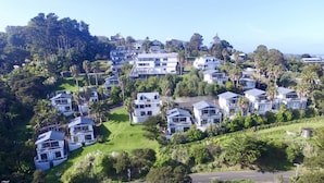 A residential area with modern houses, lush greenery, and a clear view of the ocean. - Waiheke Island Resort (Waiheke Island)