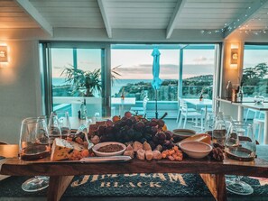 A table with a charcuterie board, glasses, and a view of the outdoors. - Waiheke Island Resort (Waiheke Island)