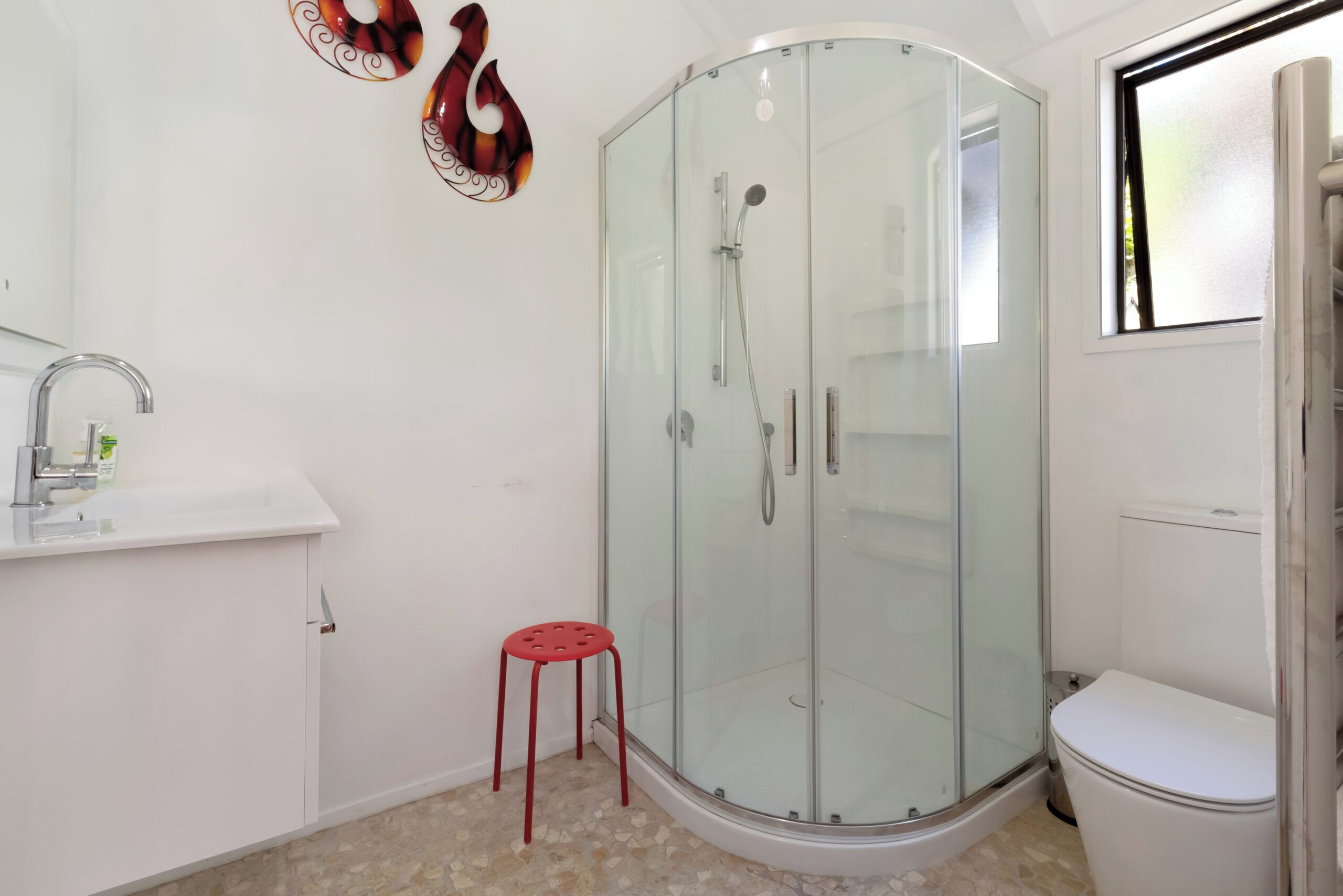 A bathroom with a glass-enclosed shower, a white sink, and a toilet.