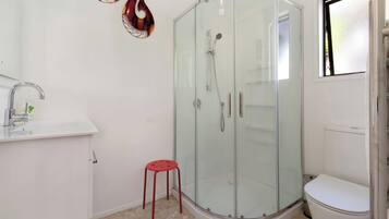 Une salle de bain avec une douche à parois de verre, un lavabo blanc et des toilettes.
