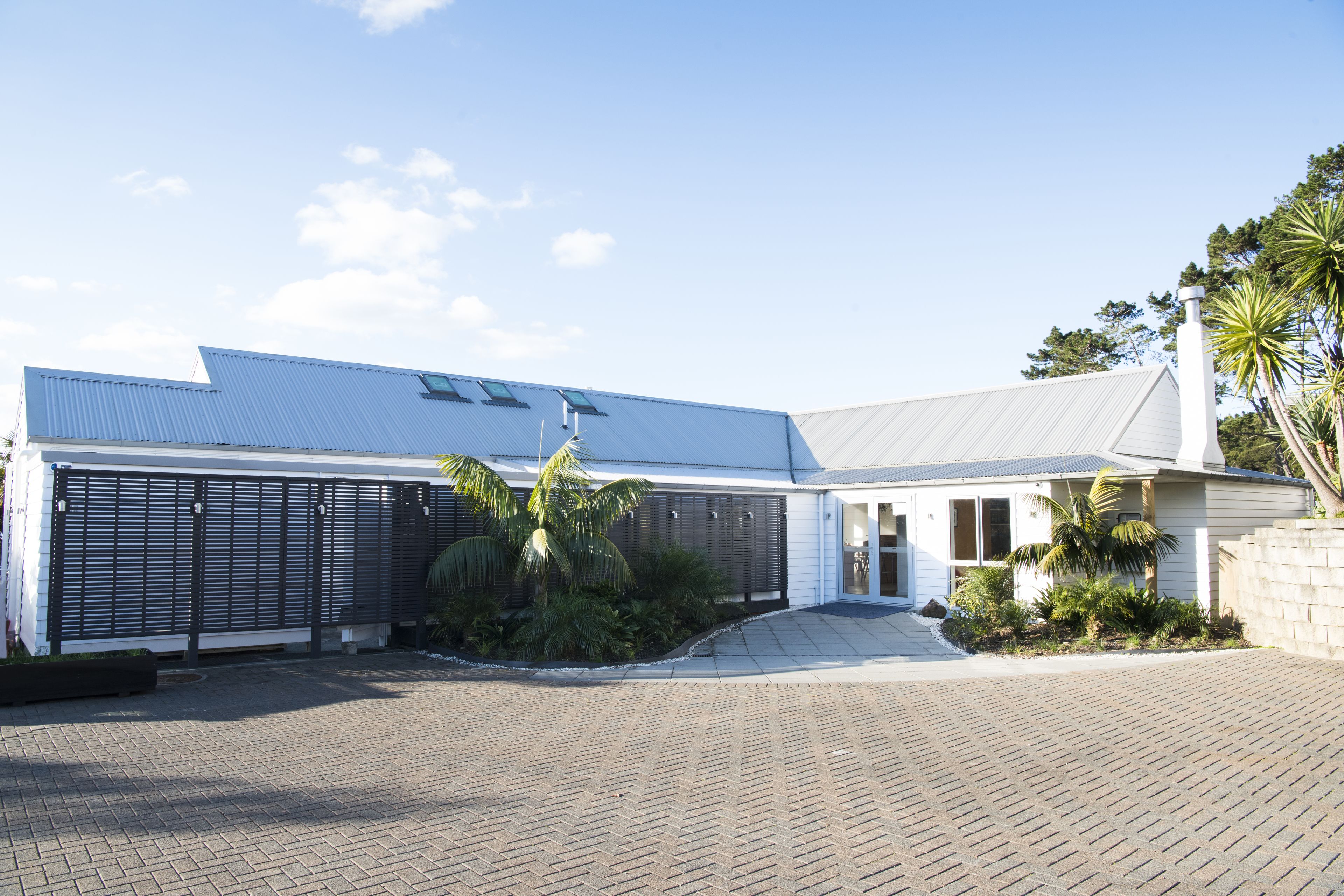 Una casa moderna con garaje, entrada cubierta y jardinería tropical.