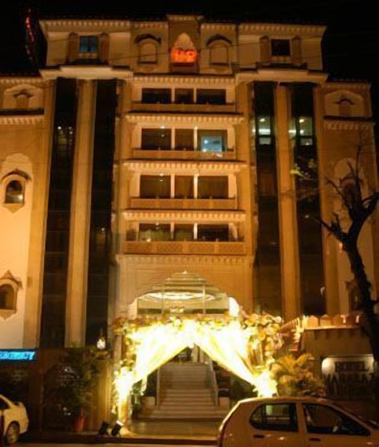 A multi-story hotel with a central entrance featuring a staircase and a decorative archway.