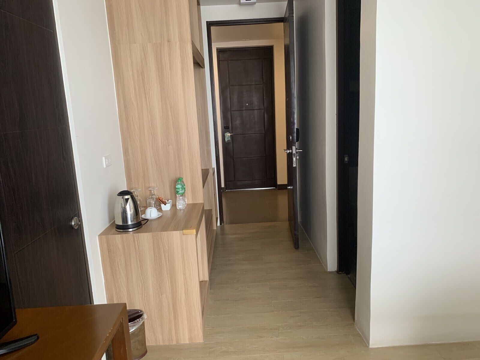 A hallway with a wooden counter, a kettle, and a bottle of water.