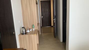 A hallway with a wooden counter, a kettle, and a bottle of water.