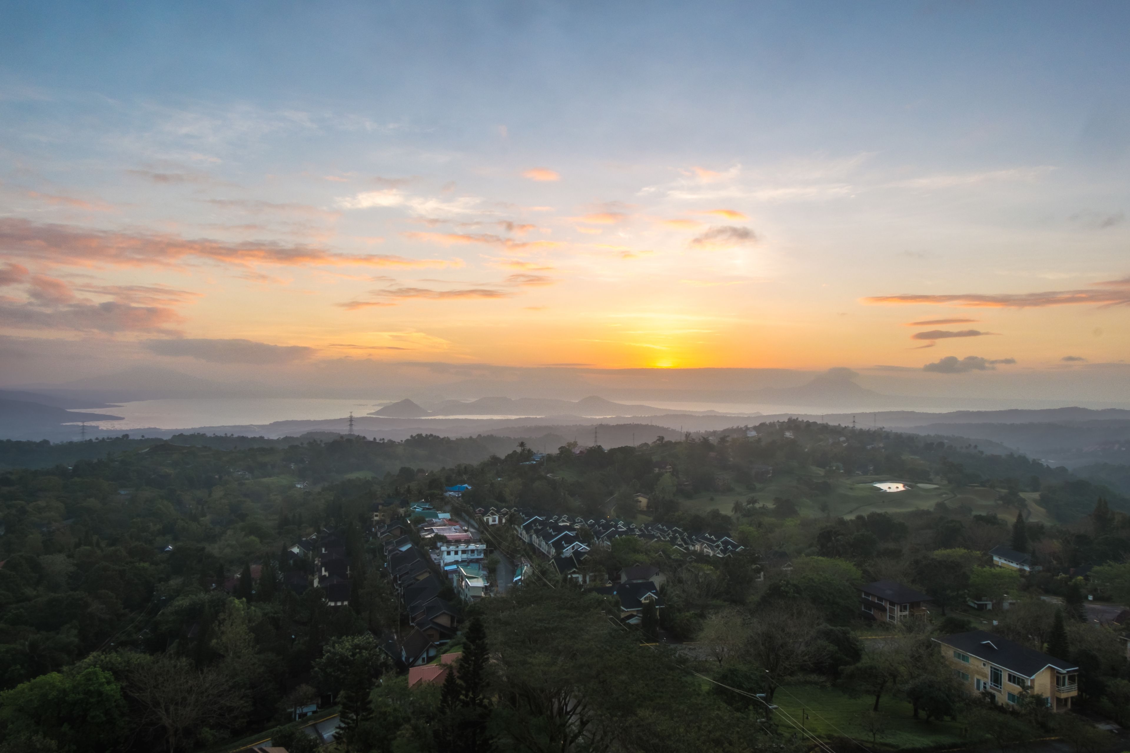 Zona residencial con casas y vista al atardecer sobre un cuerpo de agua.