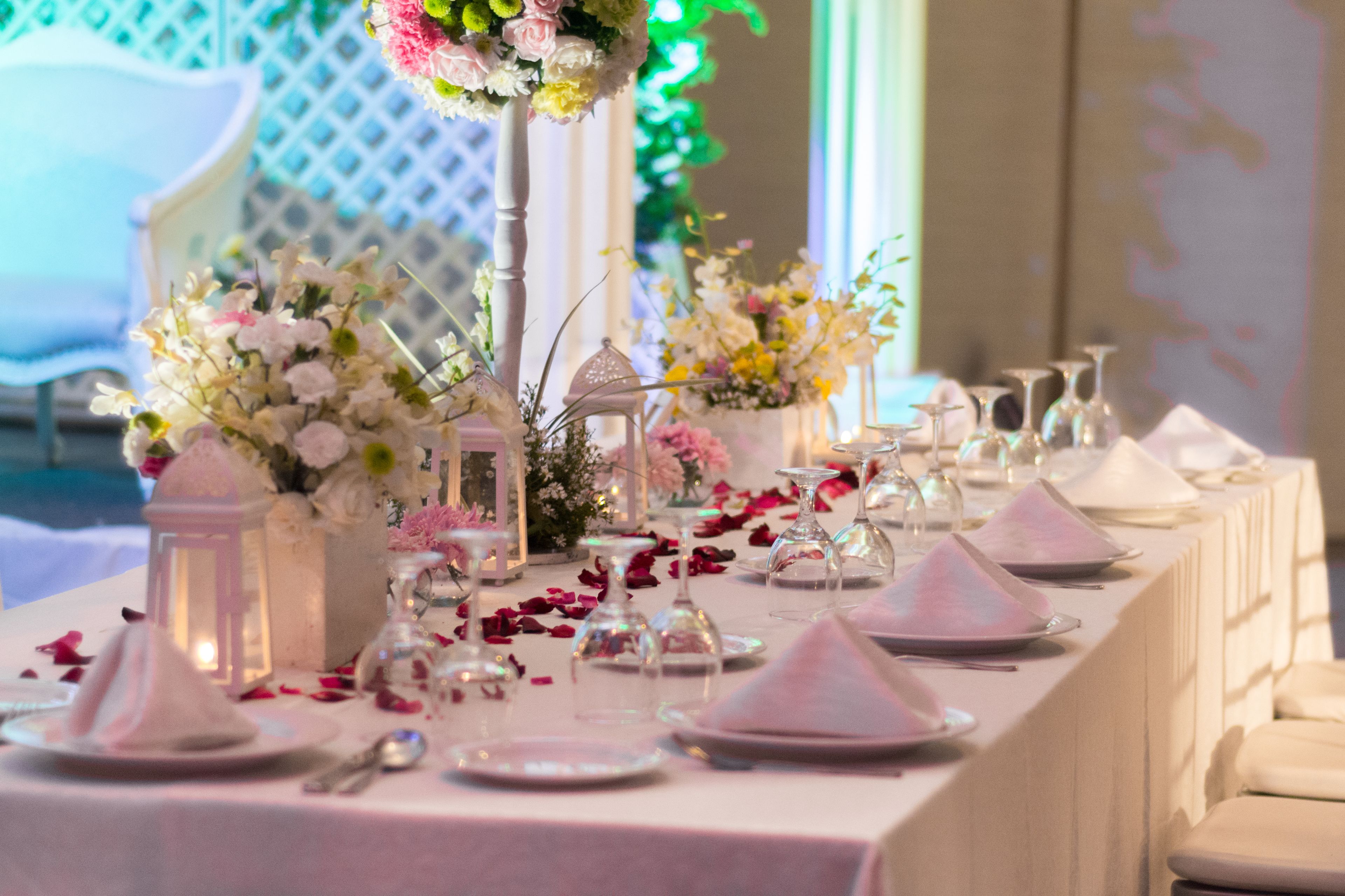 Mesa dispuesta para un evento formal, con manteles blancos, cristalería y centros de mesa florales.