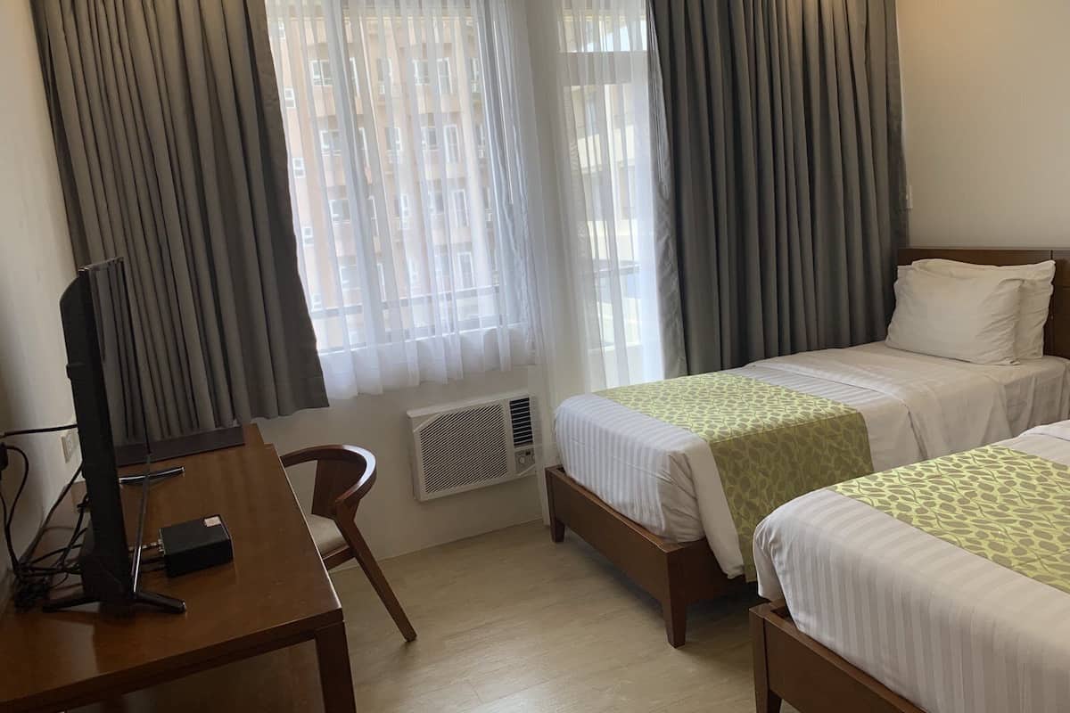 A hotel room with two beds, a desk with a computer, and a chair.