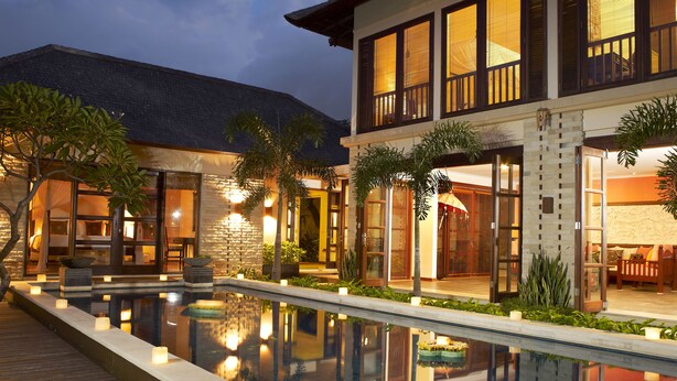 Un moderno complejo turístico con piscina, mobiliario exterior e entrada bien iluminada.