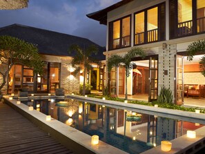 A modern resort with a swimming pool, outdoor seating, and a well-lit entrance.