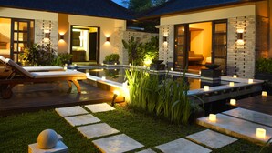 Una casa moderna con piscina, mobiliario exterior y una entrada bien iluminada.