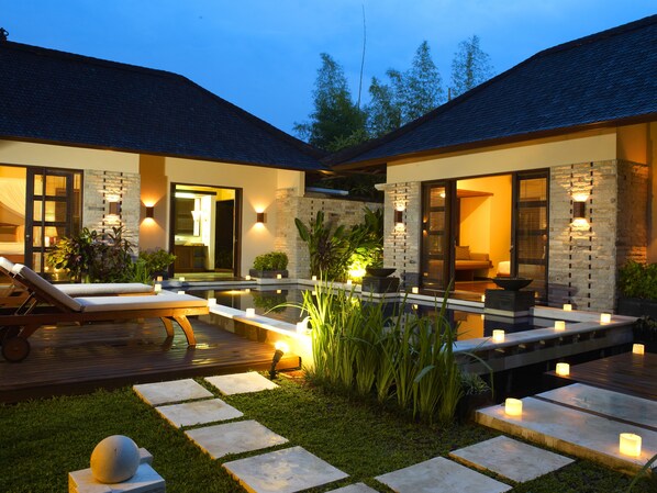 A modern house with a swimming pool, outdoor seating, and a well-lit entrance.
