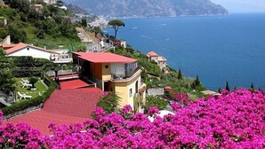 Una propiedad costera con un edificio de techo rojo, abundante vegetación y vista al mar.