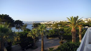 A coastal cityscape with a clear view of the sea, palm trees, and a road leading to a marina. - Lato Hotel (Agios Nikolaos)