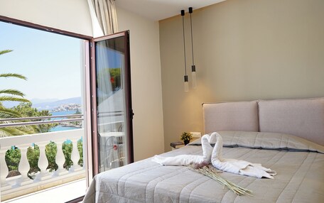 A hotel room with a bed, a balcony with a view, and a window with a plant decoration.