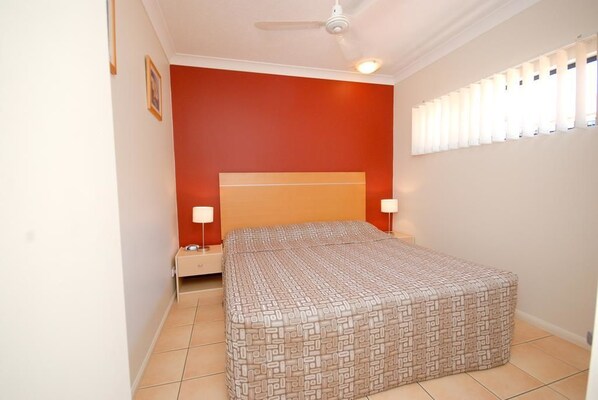 A bedroom with a bed, nightstands, a ceiling fan, and a window with blinds.