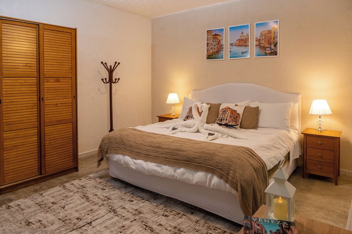 Ein Schlafzimmer mit einem Bett, zwei Nachttischen, einem Kleiderhaken und einem Kleiderschrank.