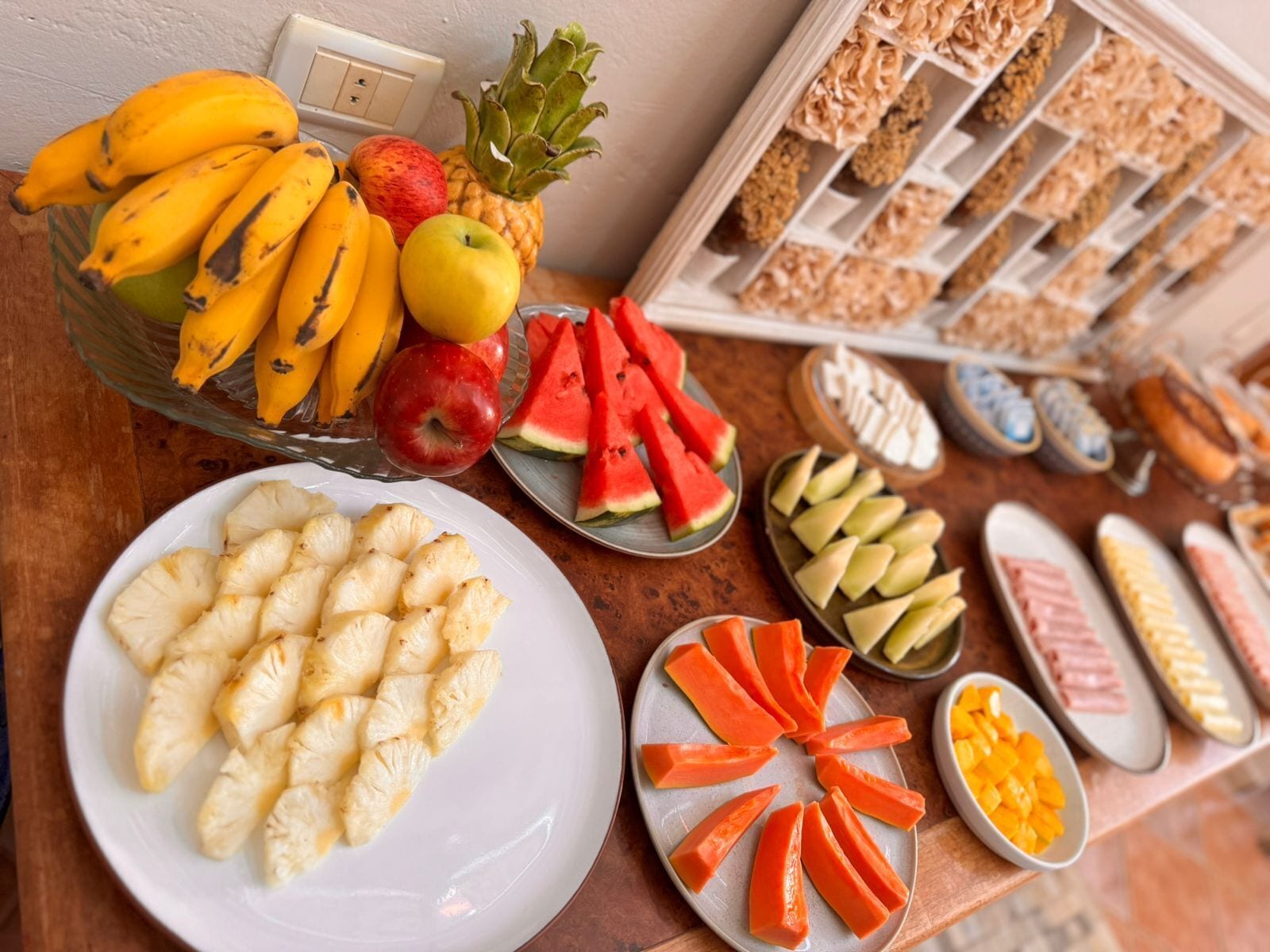 Buffet de café da manhã com frutas, legumes e doces variados.