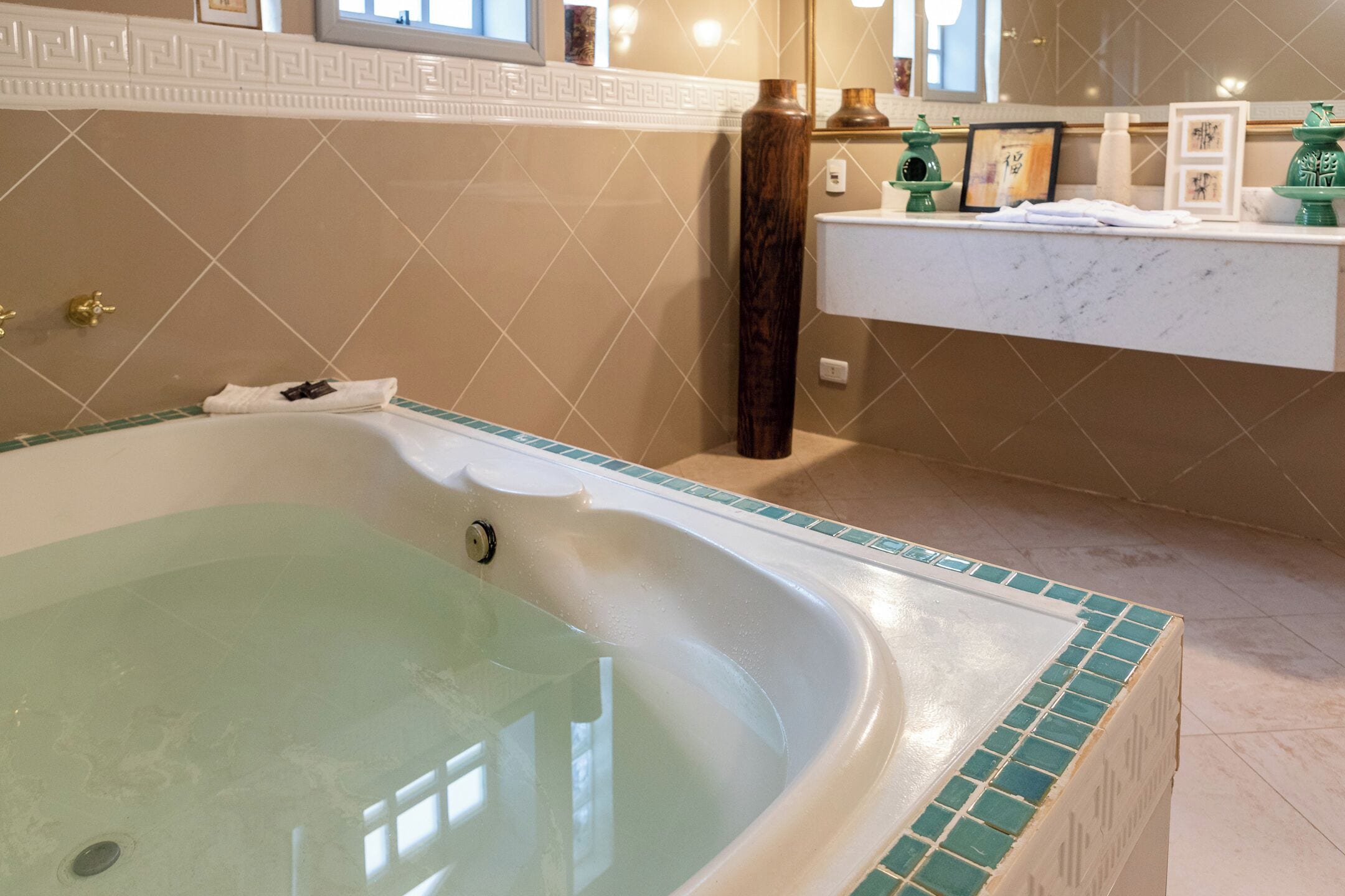 Un baño con una bañera grande, un tocador con espejo y un lavamanos.