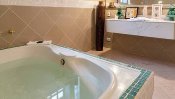 Un baño con una bañera grande, un tocador con espejo y un lavamanos.