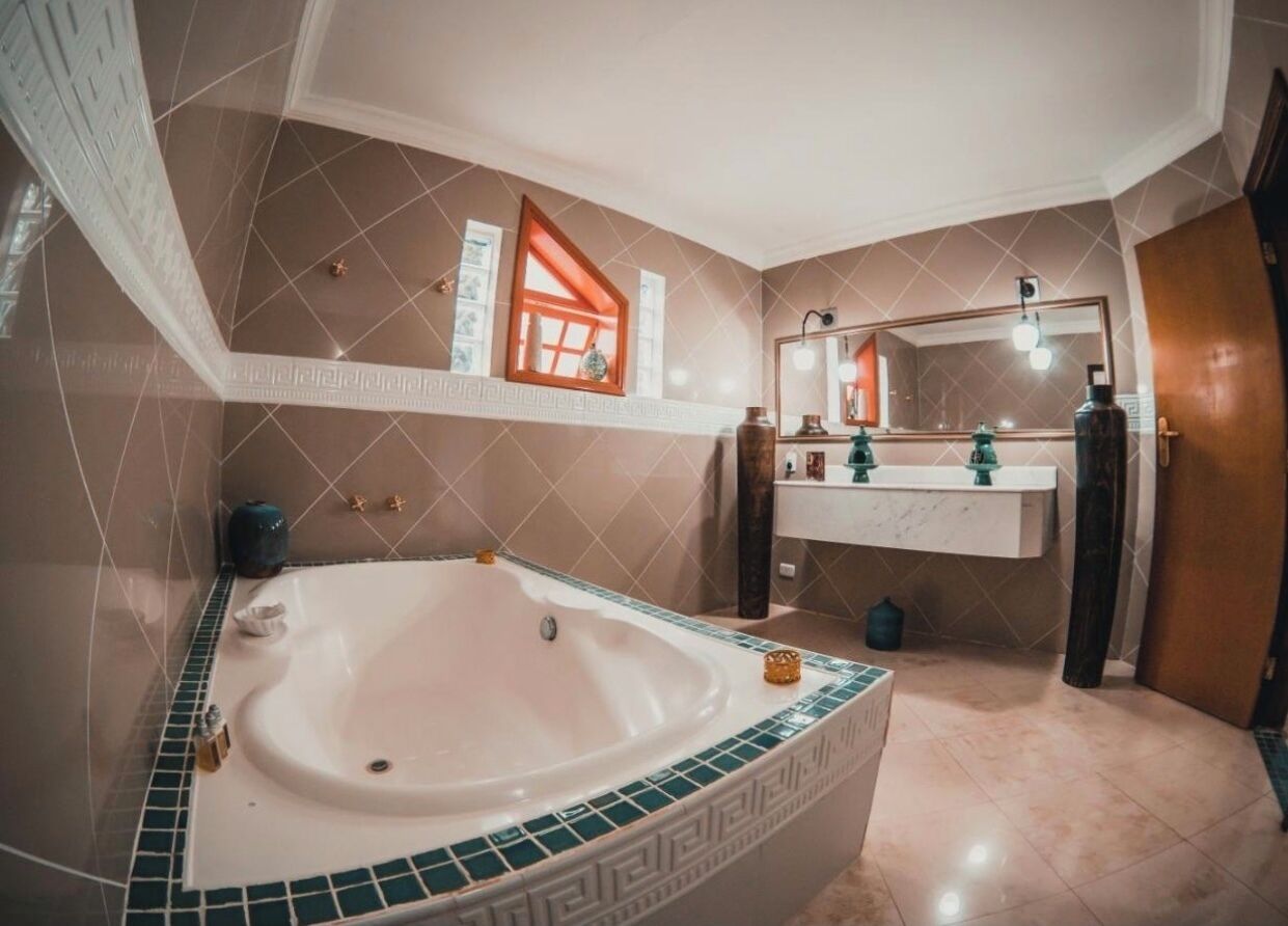 Une salle de bain avec une baignoire sur pieds, un meuble-lavabo avec un miroir et une fenêtre à cadre rouge.